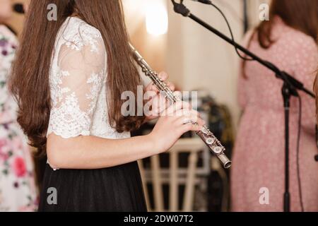 Flutista, giovane ragazza che gioca il flauto, mani, dita su tasti closeup, bambini che giocano trasversale laterale flauto, dettaglio scatto, musica classica, vento Foto Stock