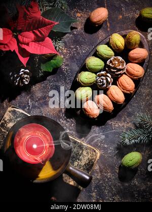 Biscotti a forma di noce con Dulce De Liche o latte condensato zuccherato. Gustoso dessert creativo su sfondo scuro con decorazioni naturali. Rametti di abete Foto Stock