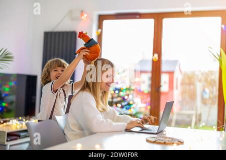 Madre cercando di lavorare da casa con i suoi figli come un'azienda Foto Stock
