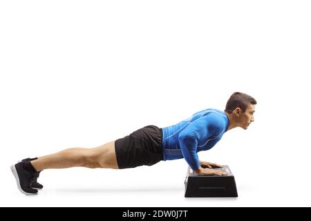 Giovane uomo forte che esercita i push-up su una piattaforma aerobica di punto isolato su sfondo bianco Foto Stock