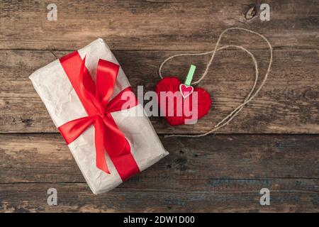 Cuore rosso e scatola regalo su sfondo di legno. Vista dall'alto, con spazio per la copia. Foto Stock