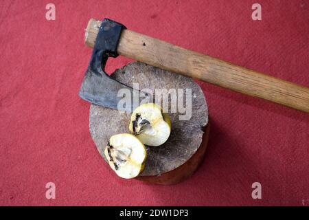 Tagliare la cotogna per mezzo di assi. Tutti rimangono su legno con sfondo rosso tappeto. Foto Stock