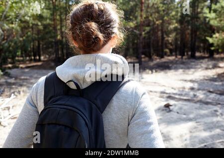 Donna escursionista con zaino che cammina sul sentiero nella foresta d'autunno, vista posteriore. Viaggio escursionistico e avventura Foto Stock