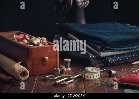 Scatola in legno di bobine di filo, mazzo di tessuti e articoli da cucire - forbici da sartoria, coltello da taglio, carta da cucire, nastro di misura, thimb Foto Stock