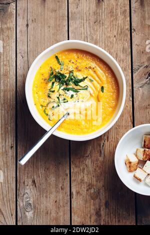 Zuppa di crema di zucca con crostini su sfondo rustico in legno. Foto Stock