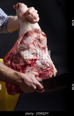 Uomo che tiene grande pezzo di maiale su sfondo nero primo piano. Foto Stock