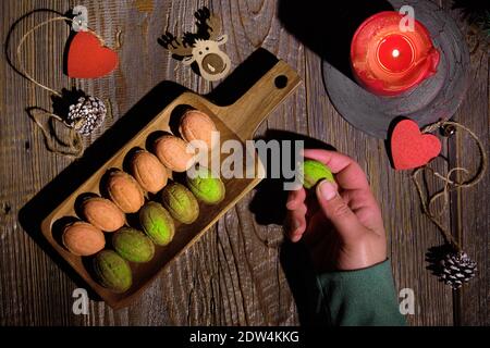 Biscotti a forma di noce con Dulce De Liche o latte condensato zuccherato. Gustoso dessert creativo su tavolo di legno scuro con decorazioni naturali - abete Foto Stock