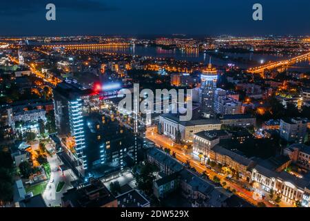 Vista aerea città notturna con strade illuminate, strade e edifici moderni in centro al tramonto notturno. Foto Stock
