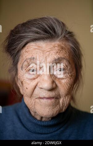 Donna carina più anziana di novanta anni caucasica con capelli grigi e rughe volto guarda la macchina fotografica, carino aspetto gentile e sorriss.Maturo nonna ritirata Foto Stock