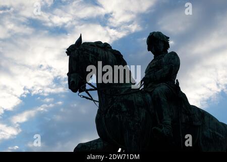 Silhouette di una statua di metallo scuro di un soldato su un cavallo, in piedi audacemente contro un cielo blu e nuvoloso. Foto Stock