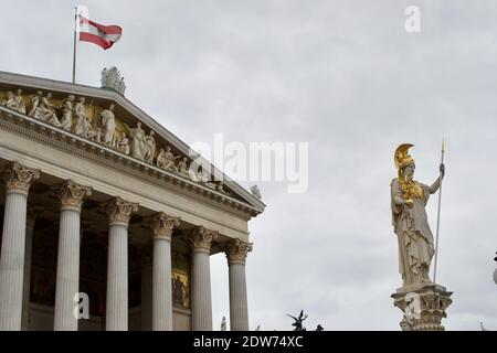 Statua in oro e pietra di una donna guerriera fuori dal Palazzo del Parlamento austriaco (Parlamentsgebäude o das Parlament); bandiera che vola e scolpito greco Foto Stock