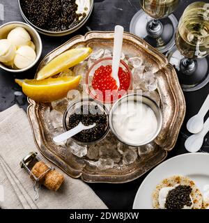 Caviale rosso e nero, mini frappè e crema acida festa antipasto su sfondo di marmo scuro Foto Stock