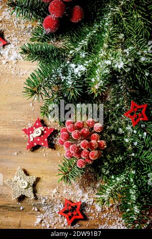 Natale nuovo anno creativo layout o biglietto di auguri con rami di abete, bacche rosse e stelle su sfondo di legno. Disposizione piatta, spazio di copia Foto Stock