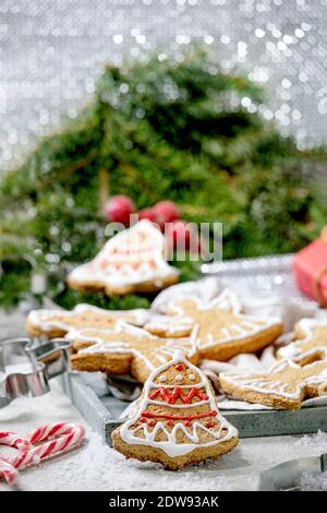 Biscotti fatti in casa con pan di zenzero natalizio con glassa ornata. Pan di zenzero uomo, angelo, campana con decorazioni natalizie su sfondo bianco bokeh. Foto Stock