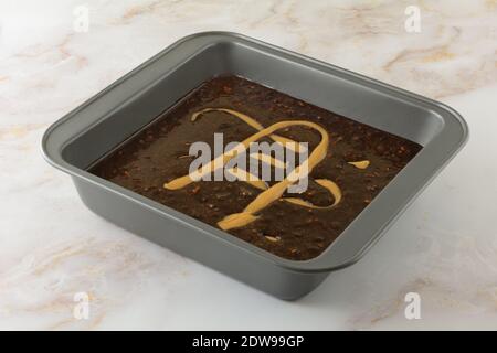 Impasto brownie crudo con caramello in teglia antiaderente sul tavolo Foto Stock