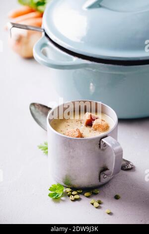 Vecchia coppa metallica di zuppa di piselli su calcestruzzo sfondo, close up Foto Stock