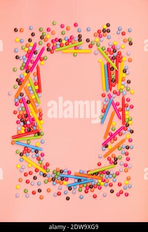 Coloratissime spruzzette e candele di compleanno su sfondo rosa, disposizione piatta, vista dall'alto Foto Stock