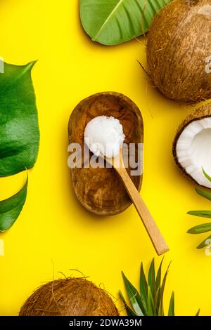 Olio di noce di cocco, foglie tropicali e noci di cocco fresco, piatto laico, vita sana nozione Foto Stock