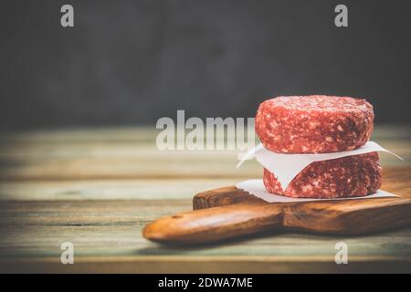 Materie hamburger - cotolette da materia organica a base di carne di manzo su sfondo di legno, lo spazio per il testo Foto Stock
