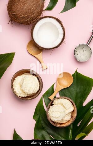 Creative laici piatta con gelato al cocco e piante tropicali su sfondo rosa Foto Stock