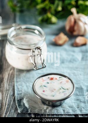 Autentica salsa raita di cetrioli pakistani su tovagliolo di lino blu su sfondo grigio di legno. Salsa di raita immergere con cetrioli, cipolla e pomodori in aggiunta Foto Stock