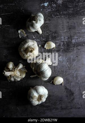 Le teste e gli spicchi d'aglio su sfondo scuro Foto Stock