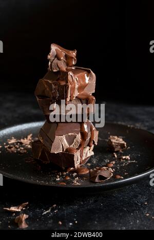 Pila di cubetti di cioccolato su sfondo nero Foto Stock