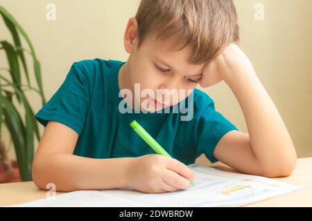 7 sì, vecchio ragazzo seduto alla scrivania e facendo i compiti. I bambini scrivono note nel notebook, compiti difficili, bambini concentrandosi sugli esempi Foto Stock