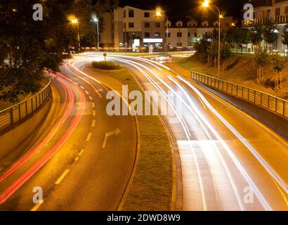 Segnaletica stradale e svolta a destra in città di notte. Foto a lunga esposizione di auto e la strada di notte Foto Stock
