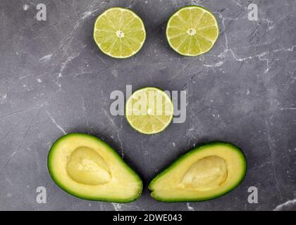 Emoticon di lime e avocado su sfondo grigio Foto Stock