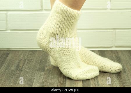 Calzini fatti a mano con fili bianchi, calzini crocheted primo piano. Foto delle gambe di una ragazza in primo piano calze a maglia. Idea di affari, guadagnando i soldi per un hobby Foto Stock