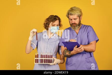 annotare le informazioni. dire no a coronavirus. rimedio antivirus in laboratorio. maschera respiratore medico. vaccino di infezione e analisi del sangue. Medico professionista di lavoro. Medico coppia uso di vaccinazione di tubo di prova. Foto Stock
