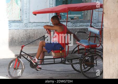 Un cubano di mezza età si trova sul suo pedicab, in attesa di un passeggero a L'AVANA, CUBA Foto Stock