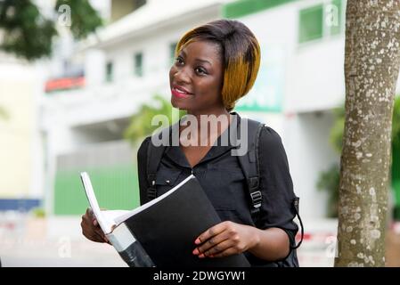 giovane studente in camicia con notebook in mano sorridente. Foto Stock
