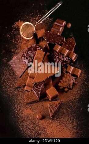 Rotture di pezzetti di cioccolato e cacao in polvere su sfondo di legno Foto Stock