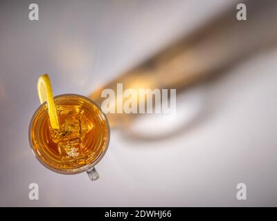 Tè freddo in vetro visto dall'alto con l'ombra di vetro sullo sfondo. Foto Stock