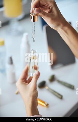 Bella donna giovane mani con olio essenziale che cade nel tubo Foto Stock