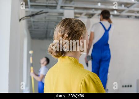 Un cliente esamina il lavoro di un lavoratore. Si alza con la schiena alla fotocamera Foto Stock