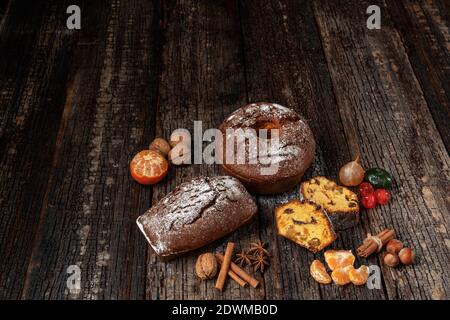 Composizione natalizia di frutta secca e stollen, con mandarino, su tavola testurizzata in legno, con spezie. A Natale. Foto Stock