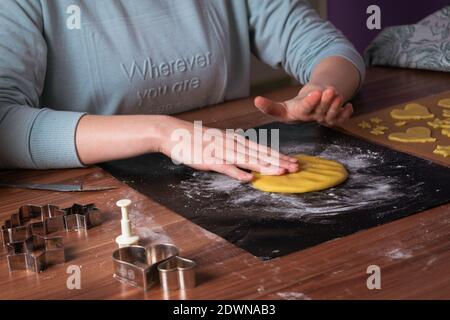 Giovane donna che prepara i biscotti di natale su carta da forno nera sopra tabella Foto Stock