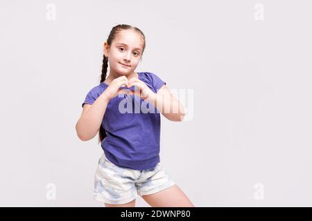 La bambina mostra il cuore con le mani su sfondo bianco Foto Stock