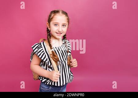 Ragazza smilante che porta lo zaino sulle spalle su sfondo rosa Foto Stock