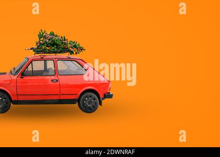 Auto retrò rossa. Albero di Natale sul tetto della macchina. Consegna di merci, viaggi di Capodanno e tour. Sfondo di Natale Foto Stock