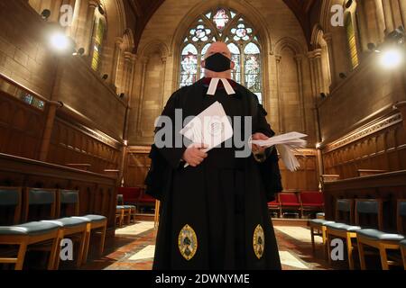 Il dottor Derek Browning, ex moderatore dell'Assemblea Generale della Chiesa di Scozia, tiene l'ordine di servizio del giorno di Natale, mentre li mette su sedie socialmente distanziate all'interno della Chiesa Parrocchiale di Morningside, Edimburgo, mentre si prepara per gli adoratori prima del servizio del giorno di Natale. Foto Stock