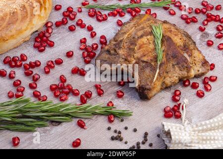 bistecca alla griglia su fondo ligneo. pezzo di carne fritta con semi di melograno e un rametto di rosmarino Foto Stock