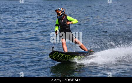 Donna Motorsurf concorrente in curva a velocità facendo un sacco di spray. Foto Stock