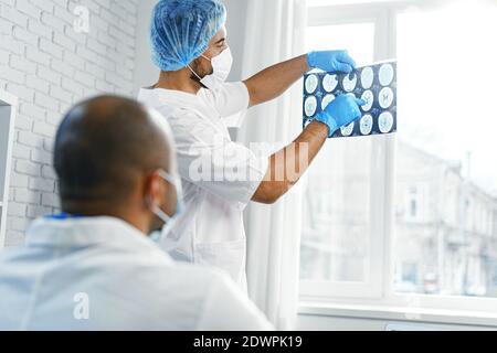 Due medici di sesso maschile esaminano la risonanza magnetica cerebrale di un paziente nel cabinet Foto Stock