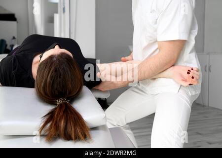 Terapeuta maschile che offre massaggio per alleviare il dolore alle spalle ad una paziente femminile in clinica fisioterofica. Foto di alta qualità. Foto Stock
