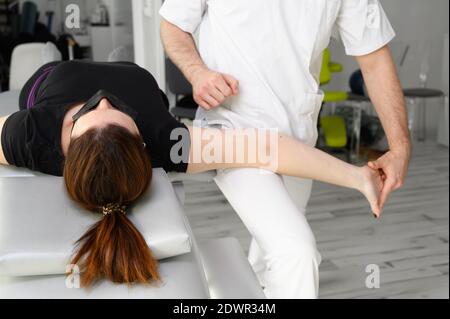 Terapeuta maschile che offre massaggio per alleviare il dolore alle spalle ad una paziente femminile in clinica fisioterofica. Foto di alta qualità. Foto Stock