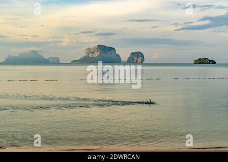 Un uomo che fa la sua nuotata mattutina in mare a Pranang Cave Beach, Railay, Krabi, Thailandia Foto Stock